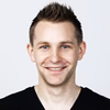 Portrait von einem lächelnden Mann mit kurzen aufgestellten Haaren.