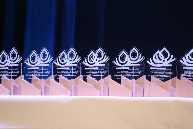 Drupal Glas-Awards stehen auf einem Tisch, mit leuchtendem Hintergrund und eleganten Motiven.
