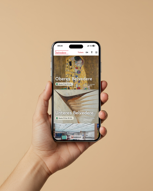Eine Hand hält ein Smartphone, das die Website des Belvedere mit Kunstwerken auf einem neutralen Hintergrund zeigt.