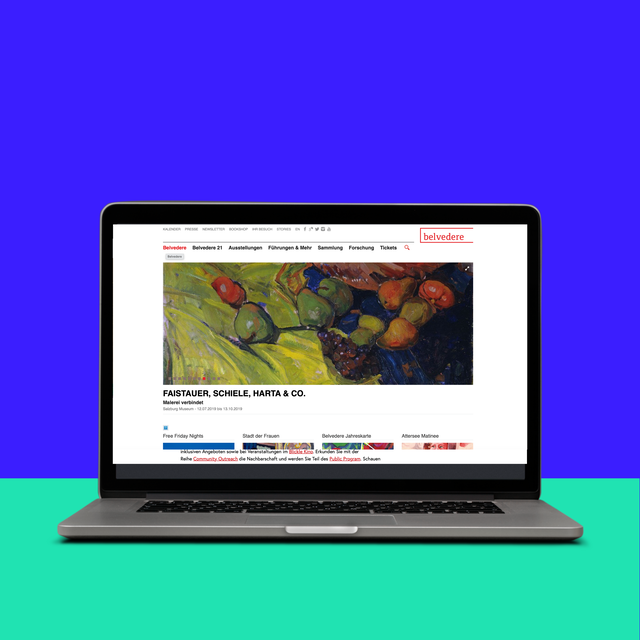 Ein Laptop zeigt eine Website mit einem bunten Gemälde von Obst auf einem leuchtend grünen und blauen Hintergrund.